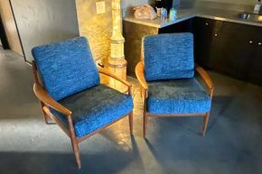 Two blue chairs are sitting next to each other in a kitchen.