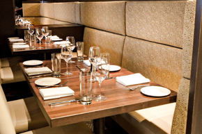 A row of tables in a restaurant with wine glasses on them
