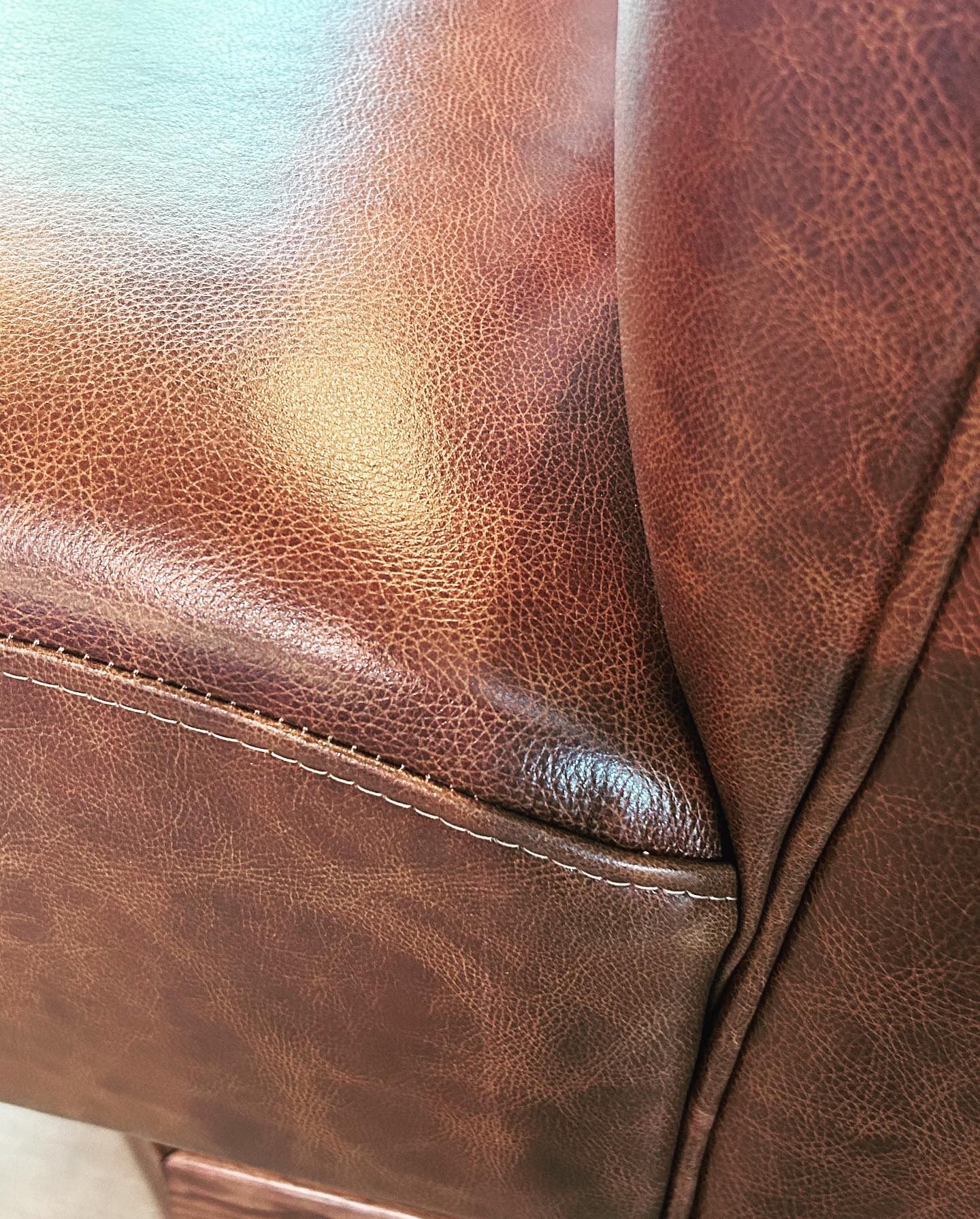 A close up of the back of a brown leather couch.
