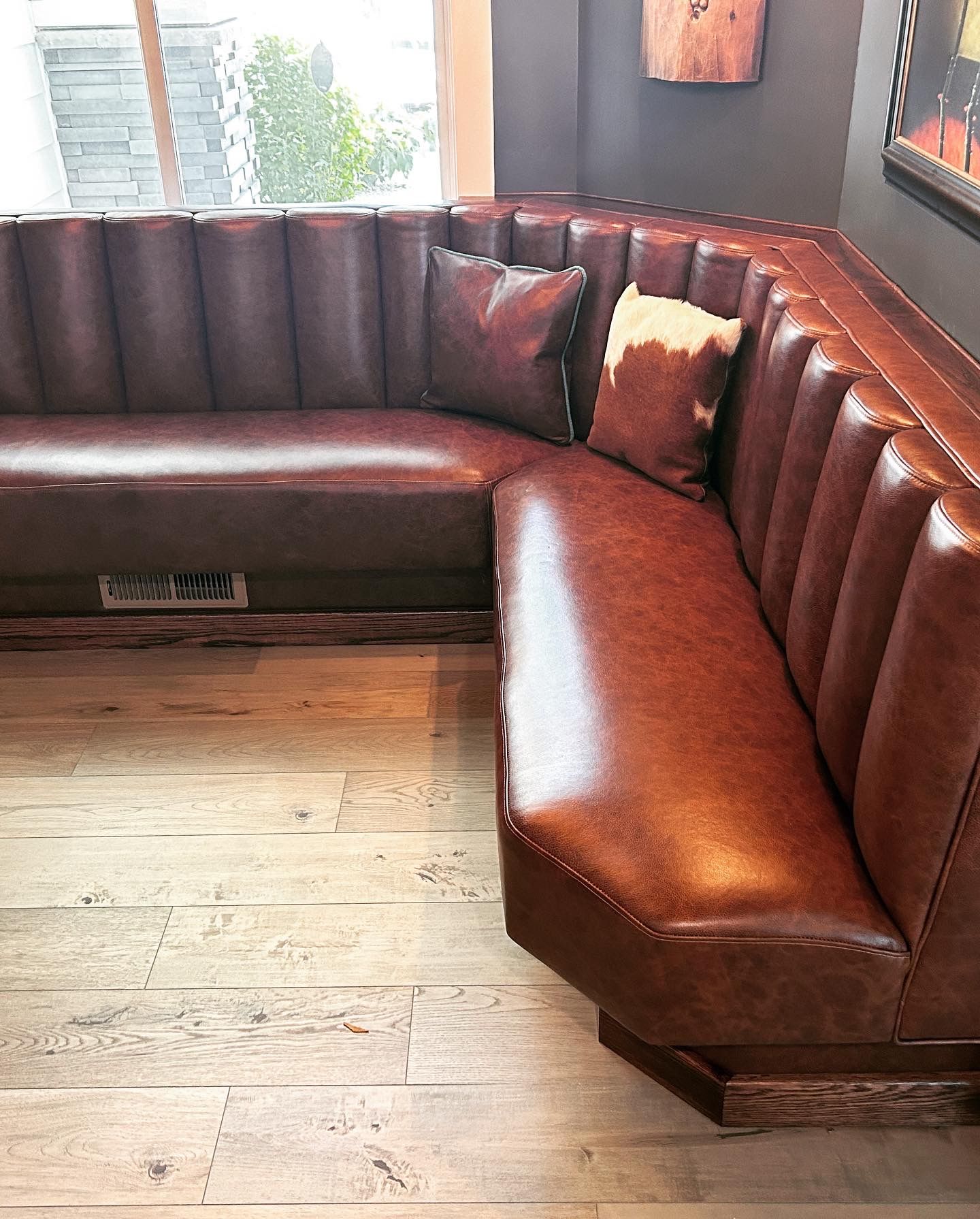 A brown leather couch is sitting on a wooden floor in a room.
