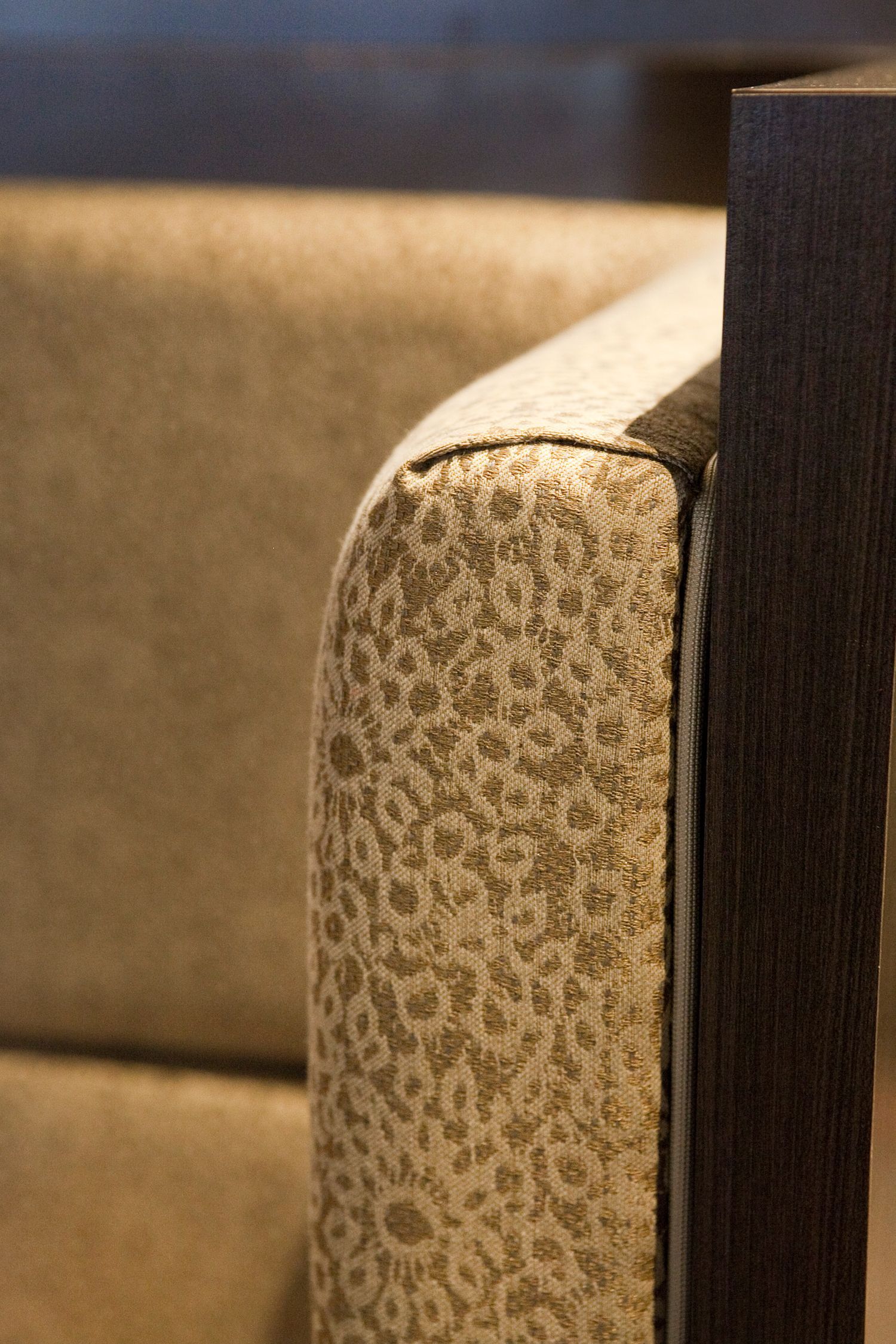 A close up of the arm of a chair with a leopard print fabric.