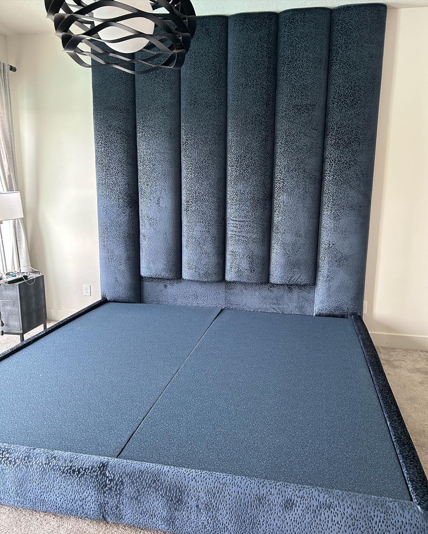 A bed with a blue headboard is sitting in a bedroom.