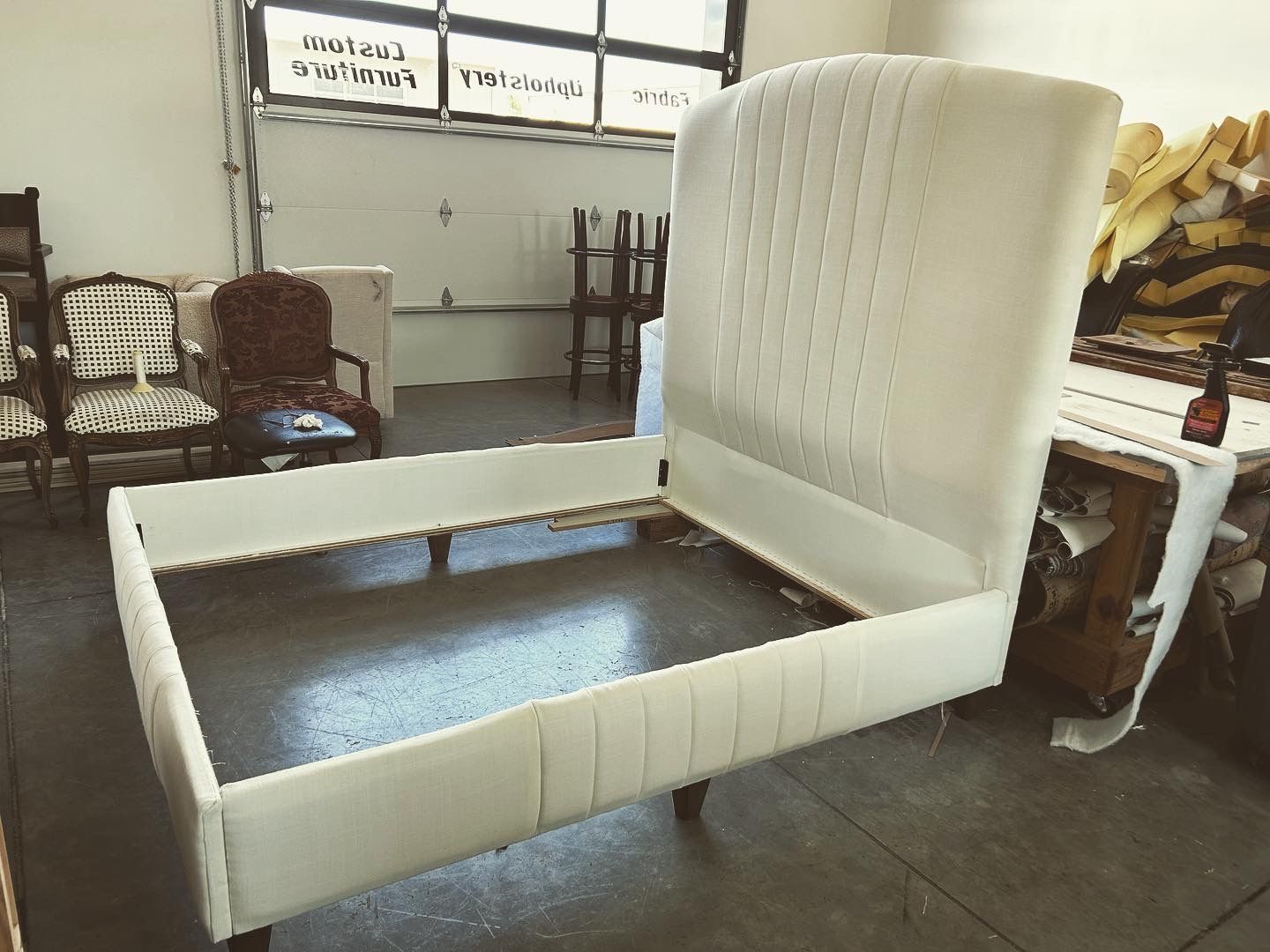 A white bed frame is sitting on the floor in a room.