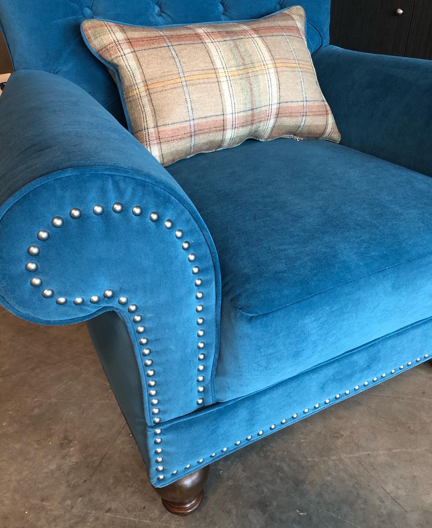 A blue chair with a plaid pillow on it