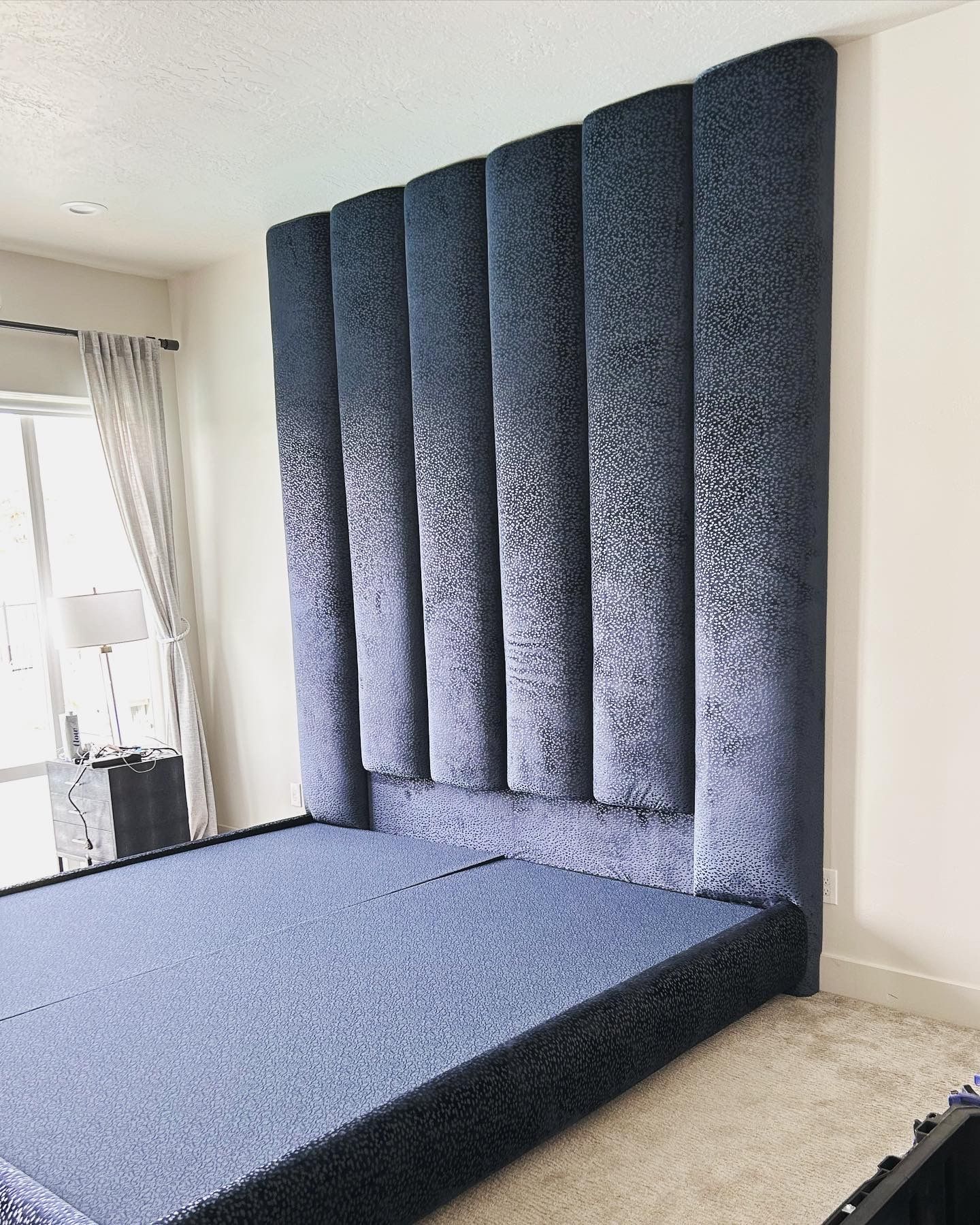 A bed with a blue headboard in a bedroom.