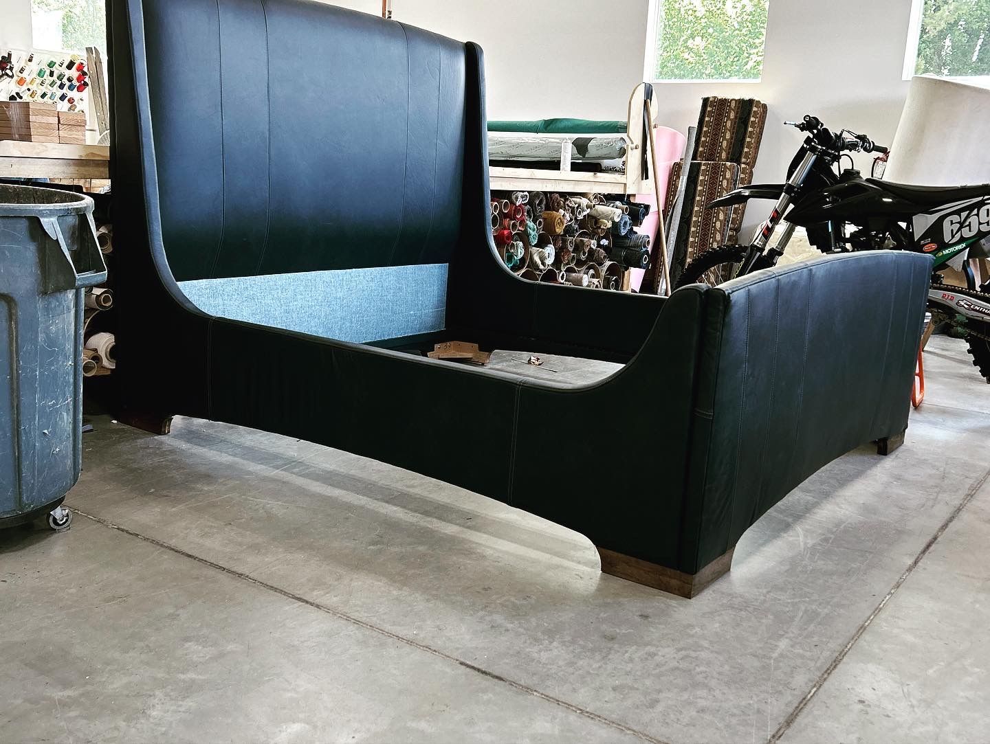 A black bed is sitting on a concrete floor in a room.