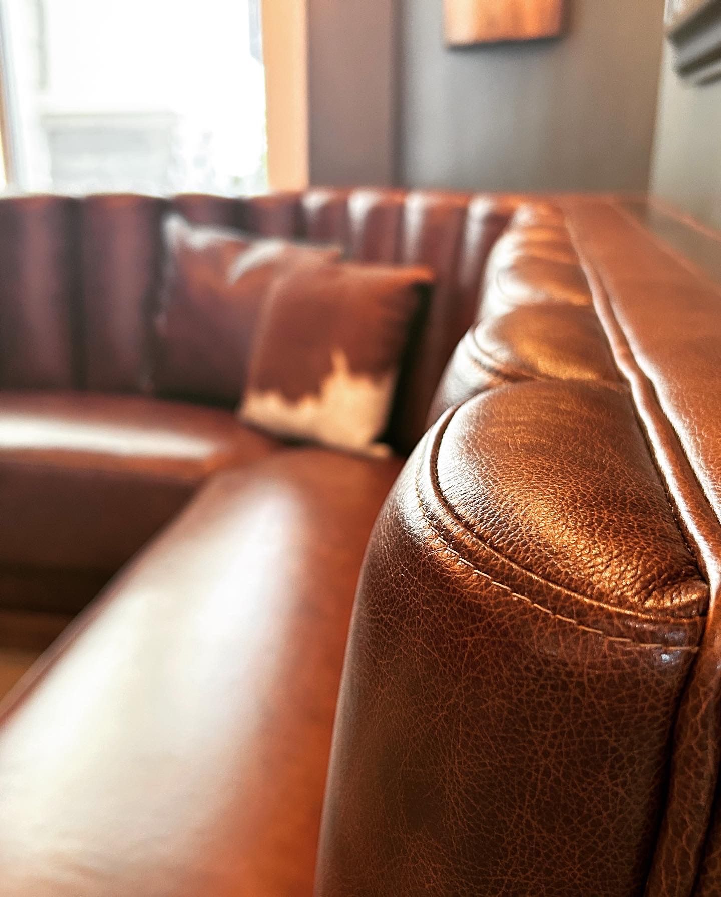 A close up of a brown leather couch in a living room.