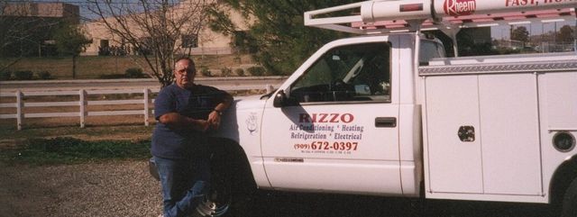 A man standing next to a white truck that says pizzo