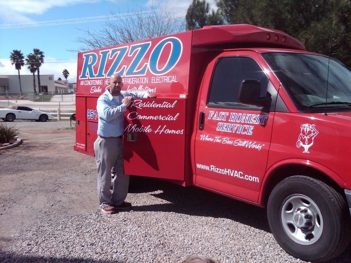 A man stands in front of a red rizzo truck