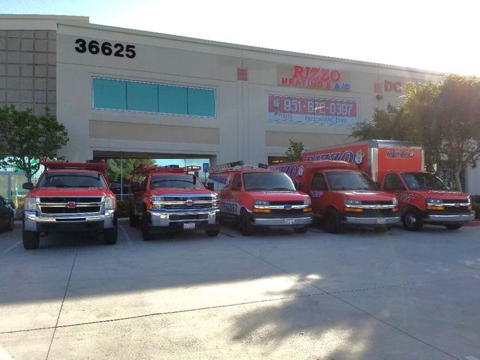 A row of red trucks are parked in front of a building.