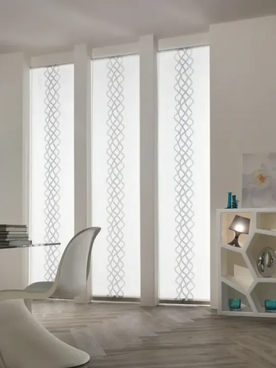 Stanza moderna bianca con alte finestre satinate, una sedia bianca e una piccola mensola con oggetti decorativi.