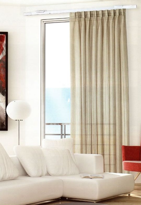 Luminoso soggiorno con divano bianco, lampada da terra, poltrona rossa e tende beige vicino alla finestra.