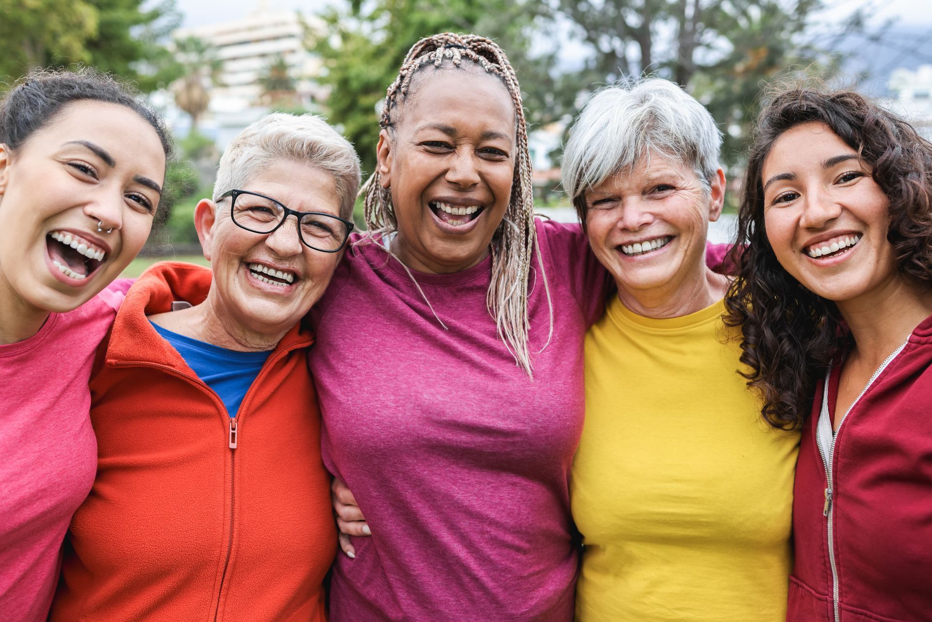Five women smiling and embracing outdoors and their hormone health.