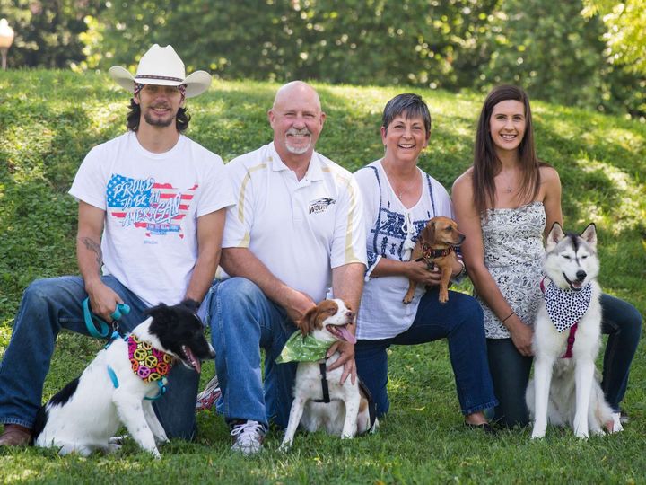 A family is posing for a picture with their dogs.