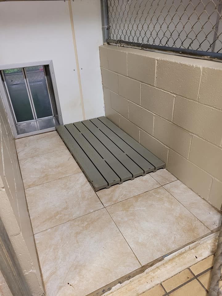 A dog kennel with a tiled floor and a fence.