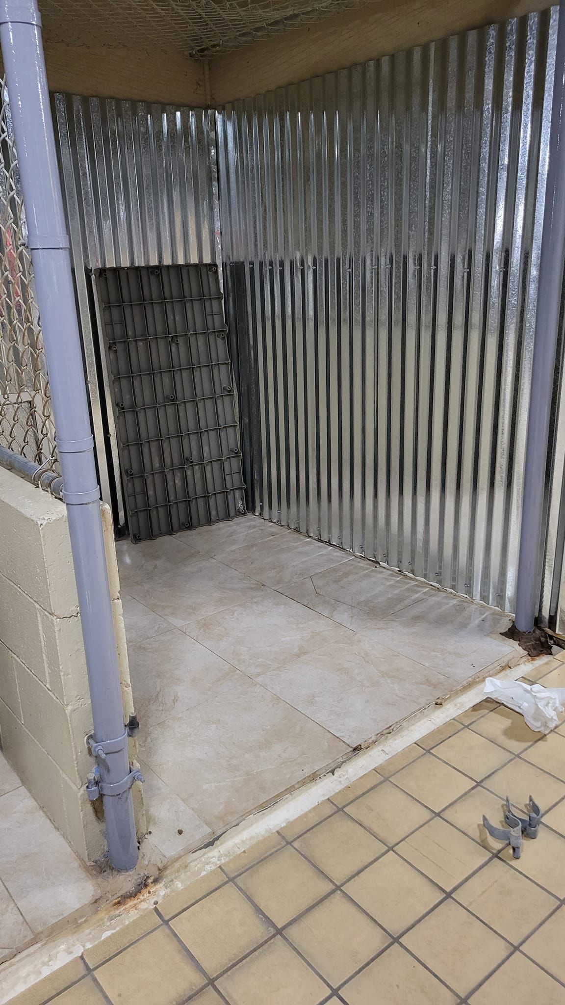 A metal fence is surrounding a room with a door.