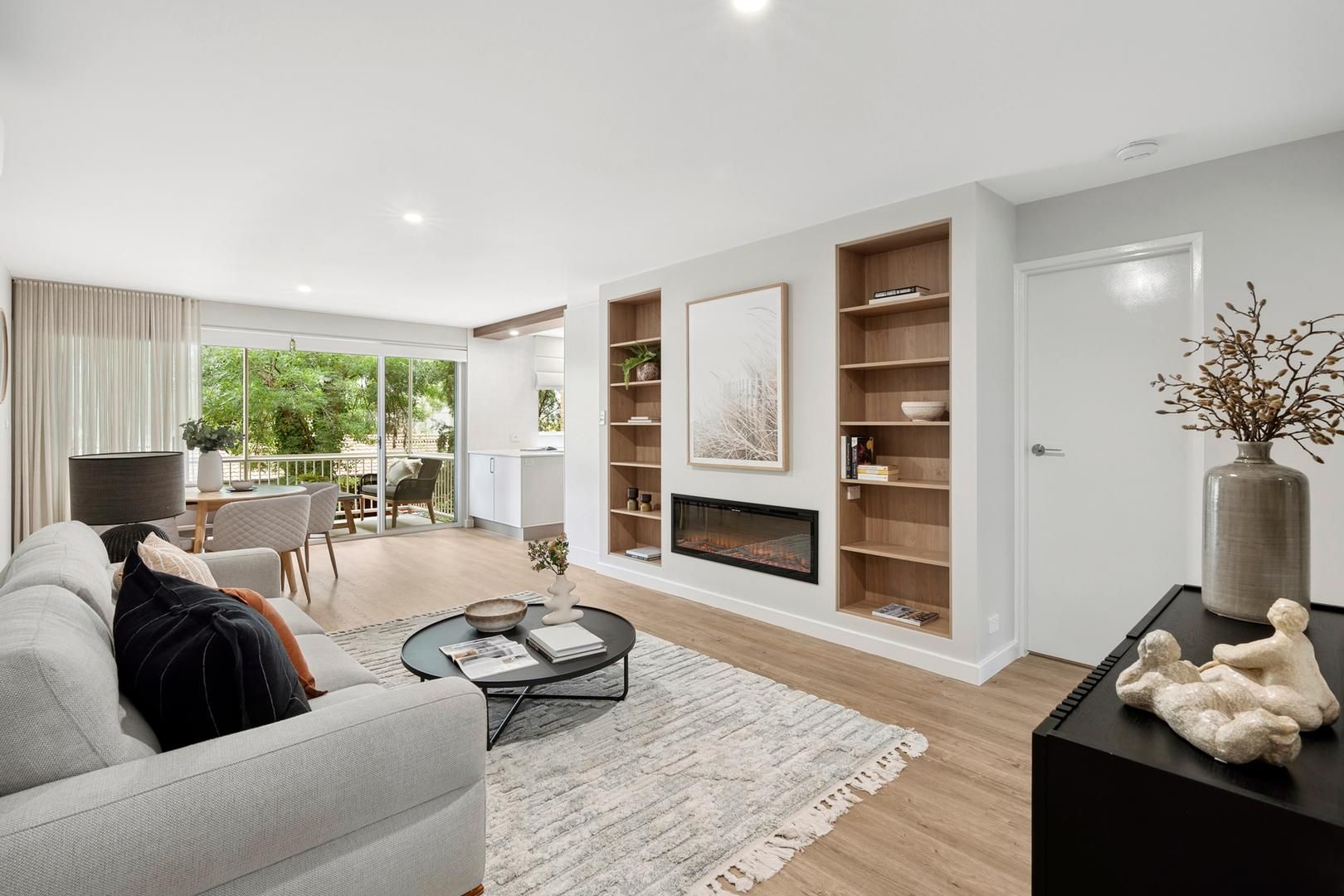 A living room with a couch , coffee table , fireplace and shelves.