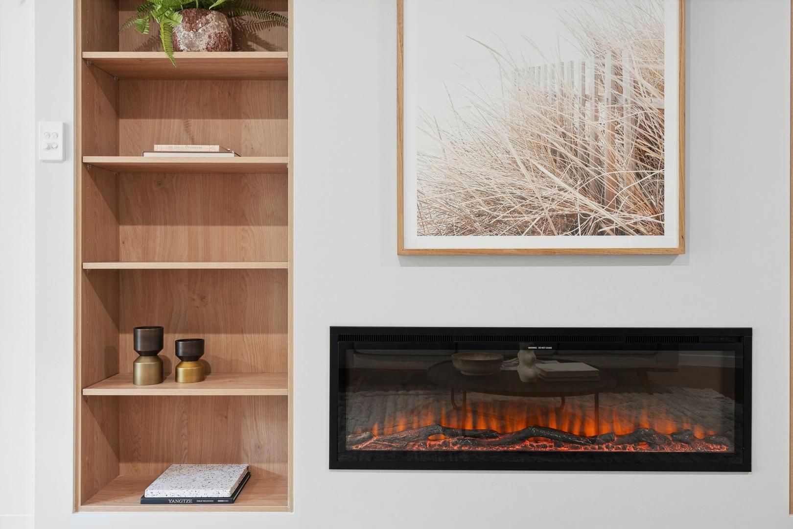 A living room with a fireplace , shelves , and a picture on the wall.