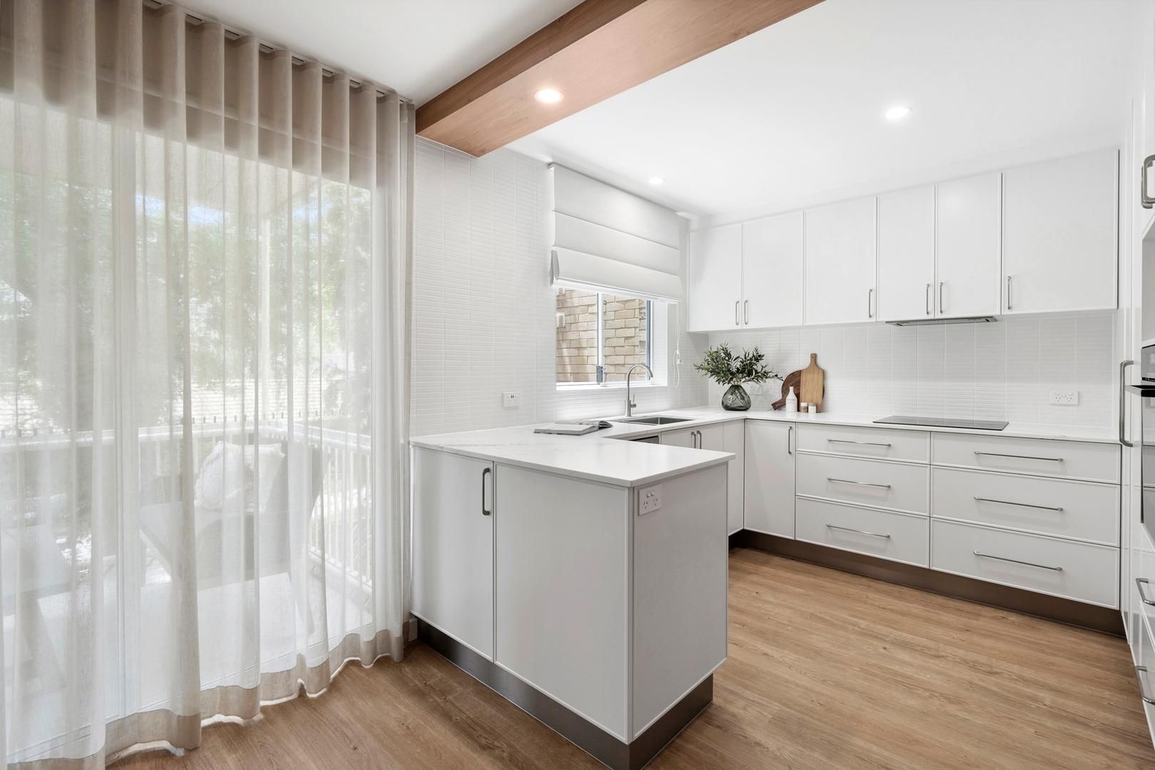 A kitchen with white cabinets , wooden floors , and a large island.