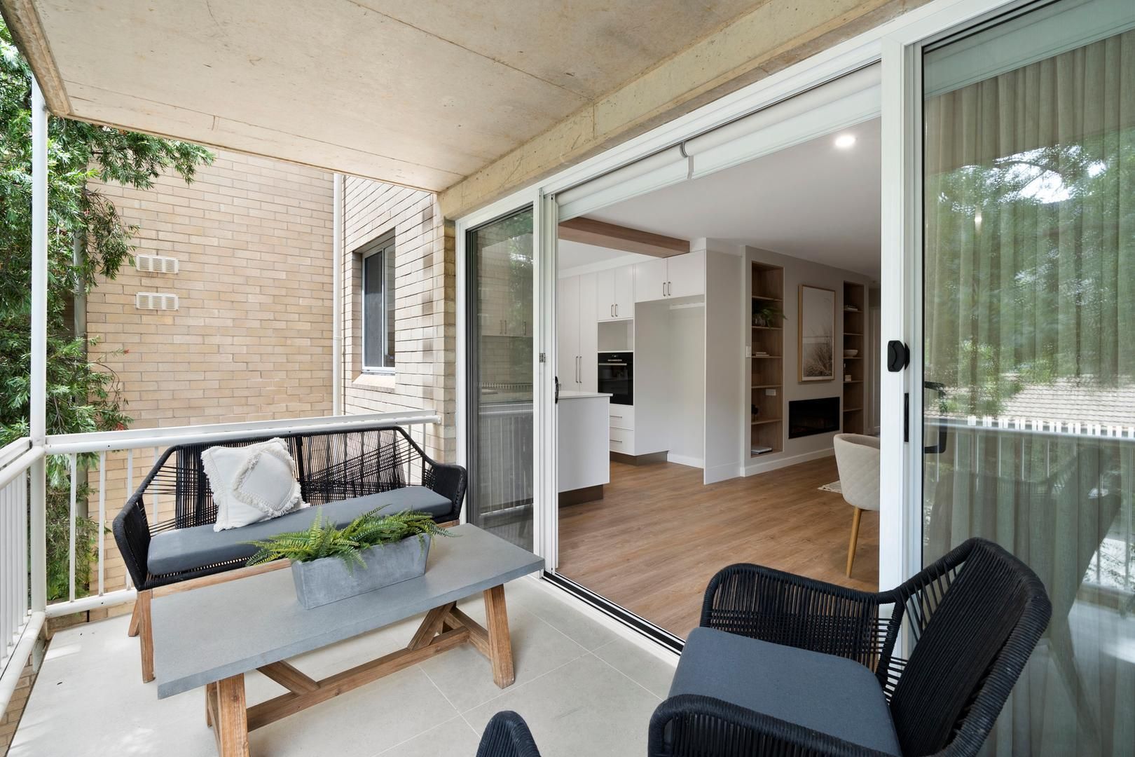 A balcony with a table and chairs and sliding glass doors leading to a living room.