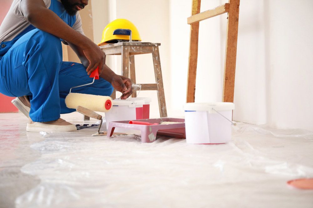 A Skilled Man Paints A Wall With A Paint Roller and Colour Buckets — Professional Painters in Kingscliff, NSW