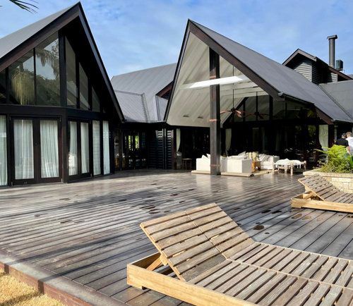 A Large House With A Wooden Deck And Chairs In Front Of It — Professional Painters in Suffolk Park, NSW