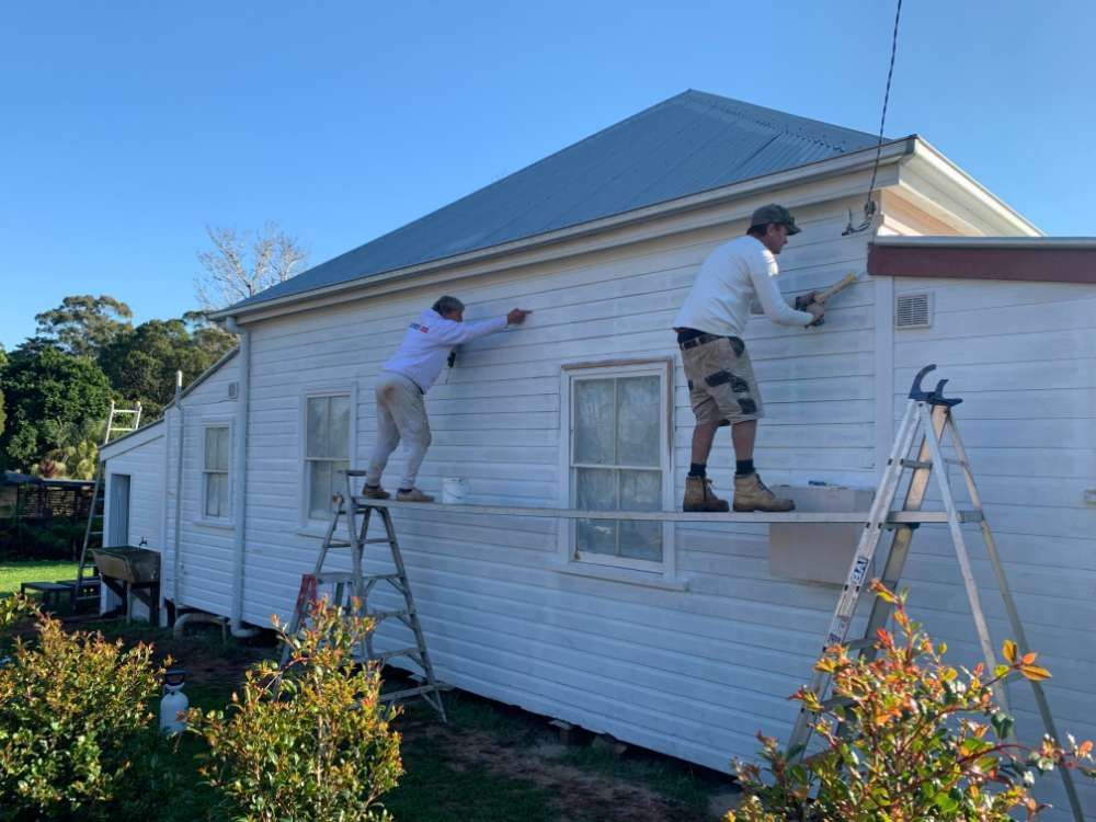 Two Men Are Painting the Side of a White House — Professional Painters in Suffolk Park, NSW