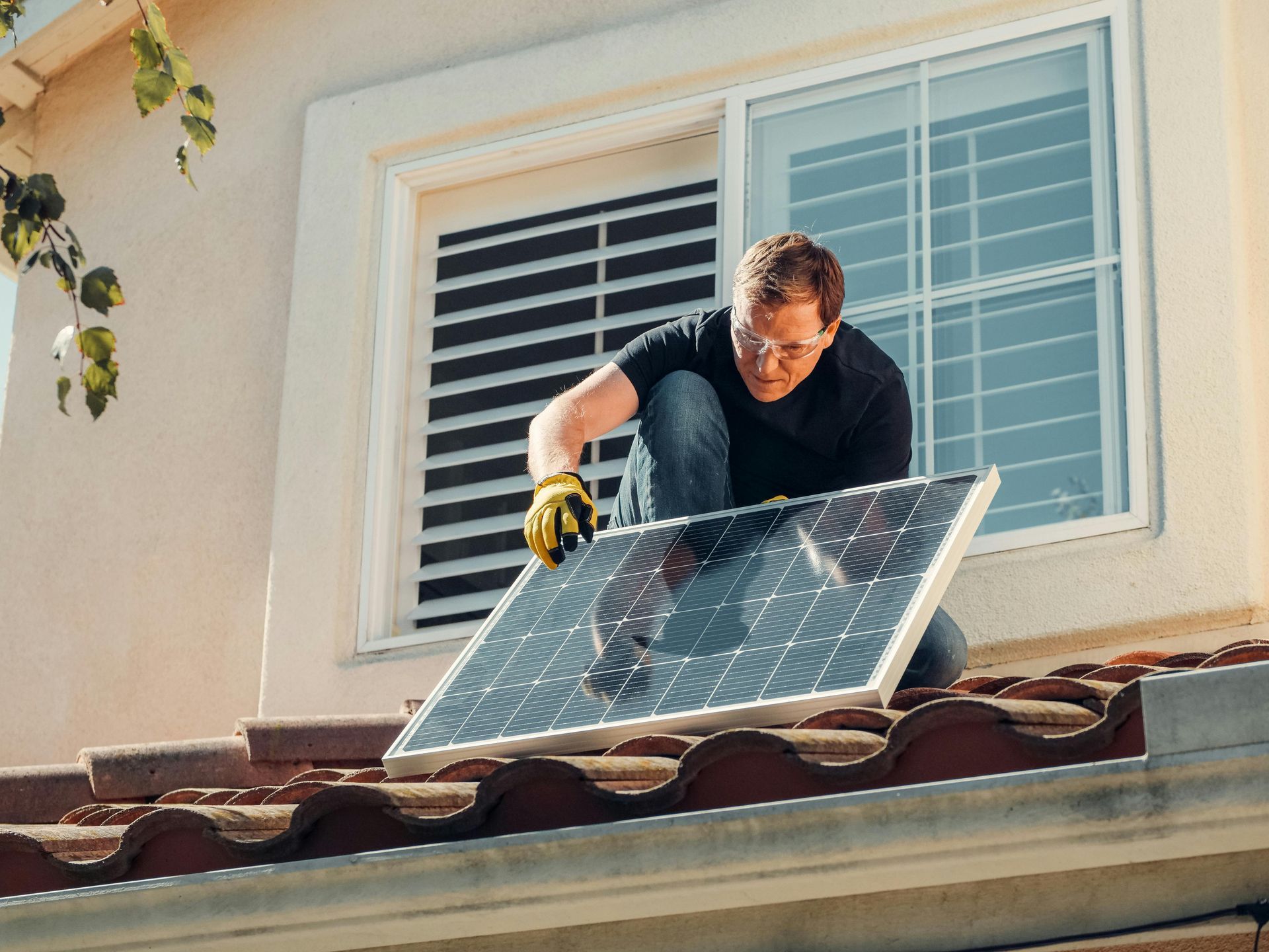 A man is installing a solar panel on the roof of a house.