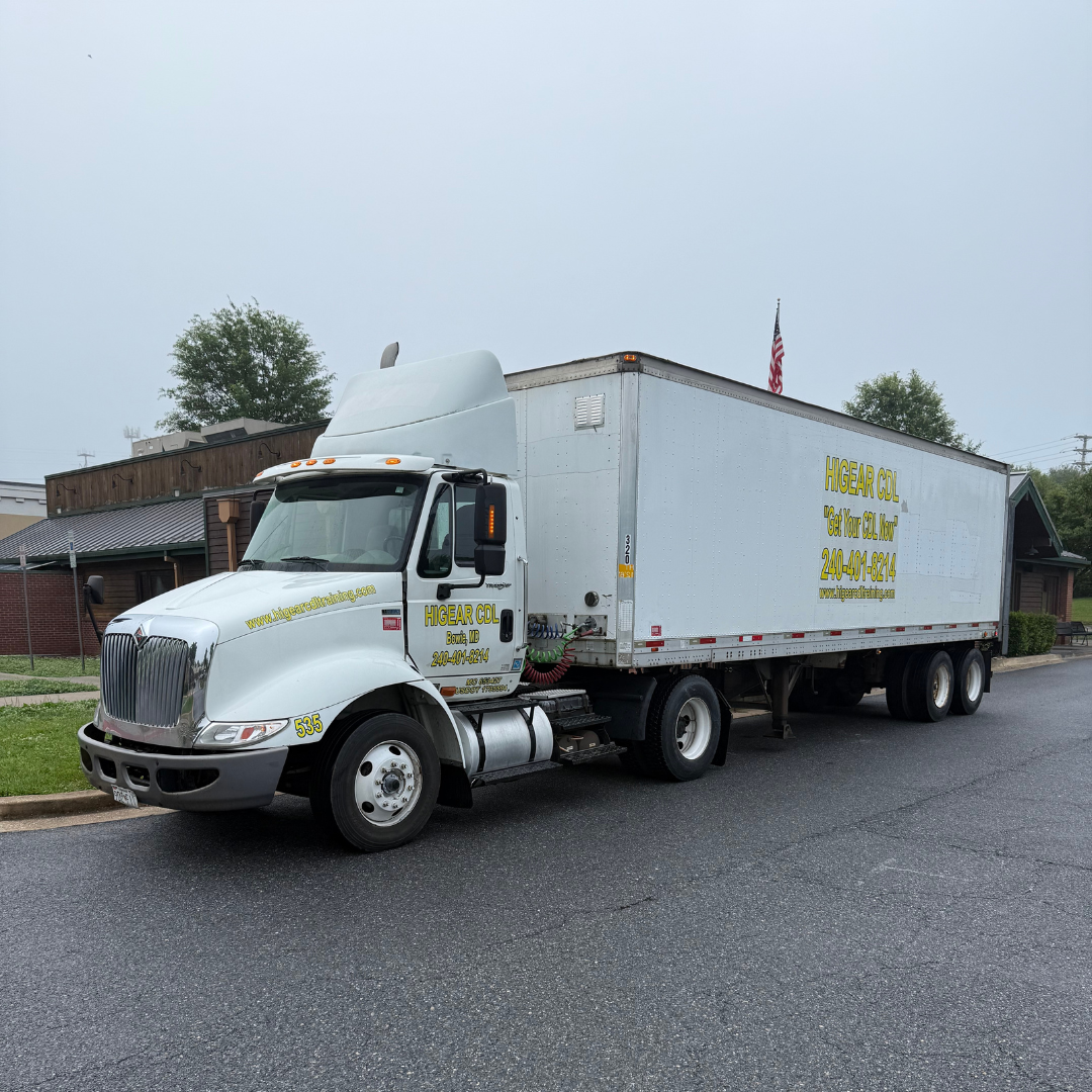 A white semi truck with a trailer is parked on the side of the road.