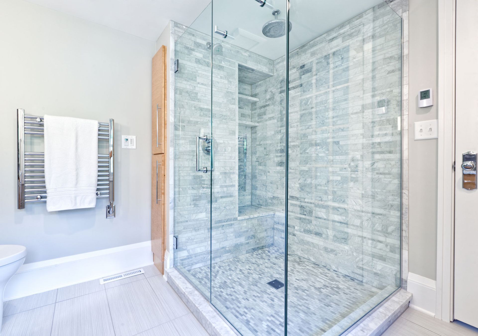 A bathroom with a walk in shower with a glass door.