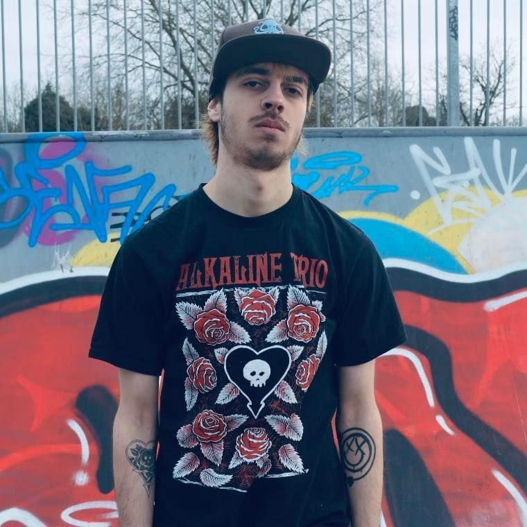 A man wearing a black shirt that says alkaline rio