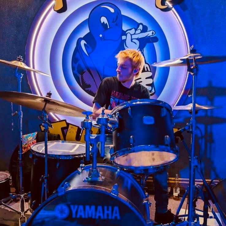 A man playing drums in front of a yamaha drum set