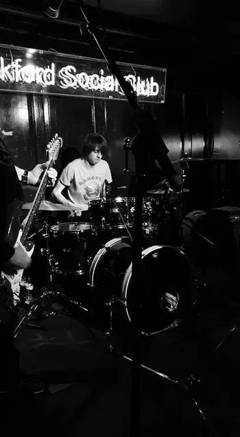 A black and white photo of a group of people playing instruments on a stage.