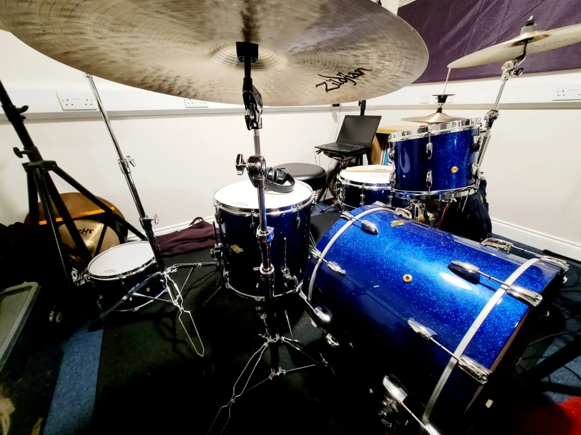 A blue drum set is sitting on a black floor in a room.