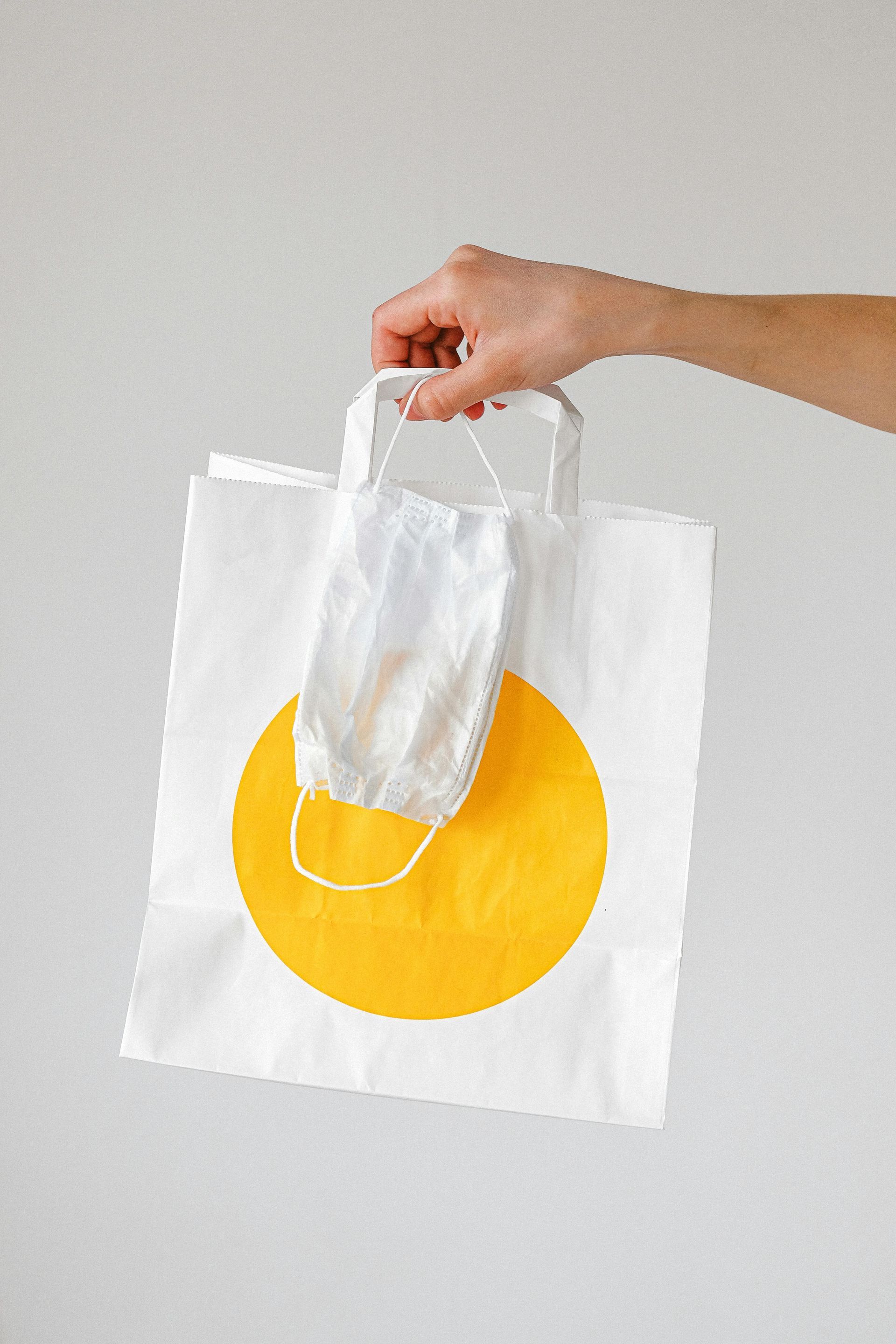 A person is holding a paper bag with a mask in it.