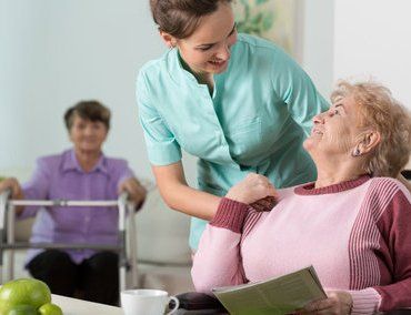 A female nurse talking to a seated elderly woman