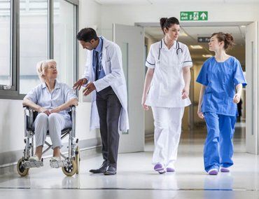 A group of nurses and a doctor walking next to a person in a wheelchair