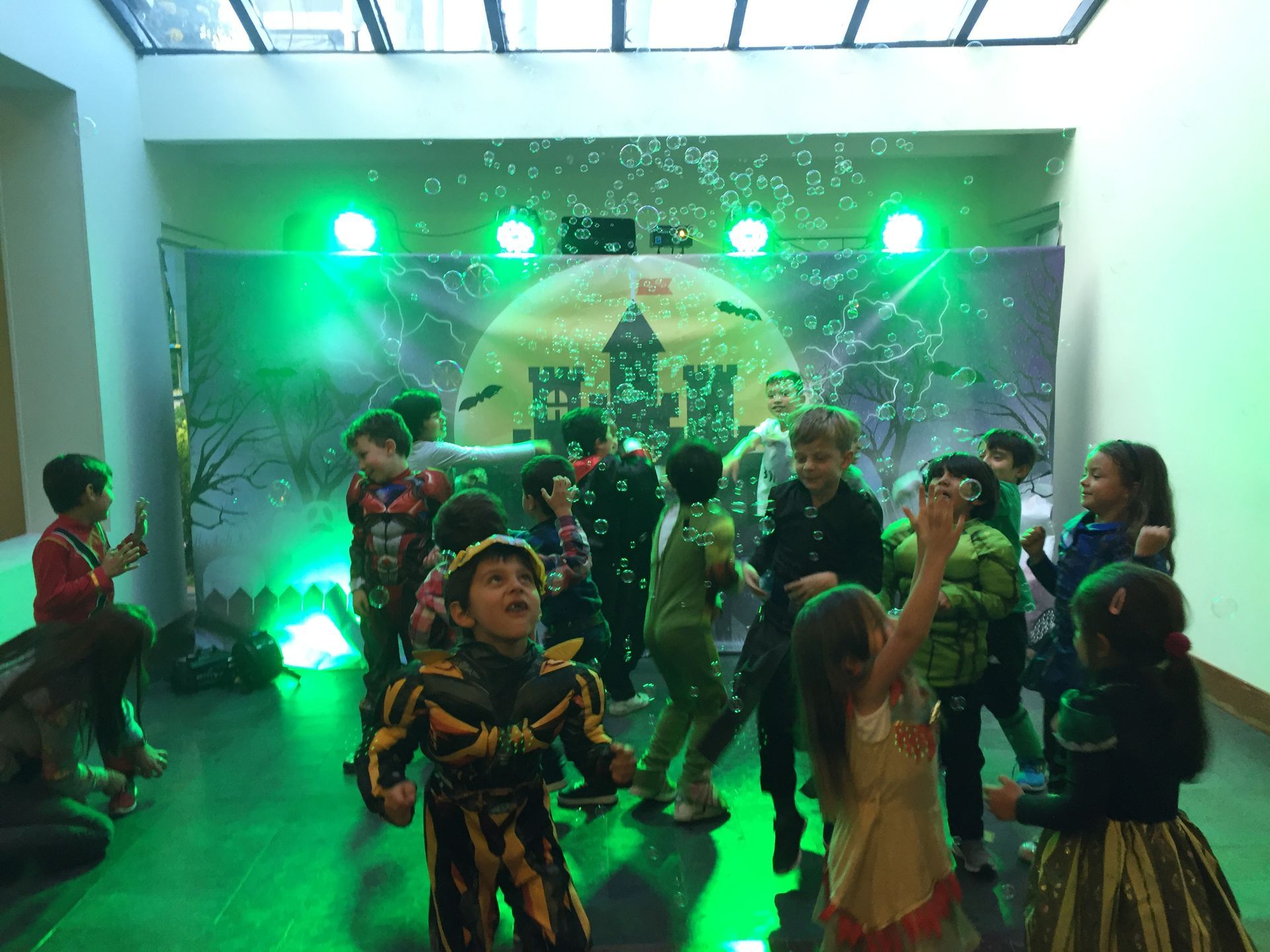 Un grupo de niños está bailando en una habitación con luces verdes.