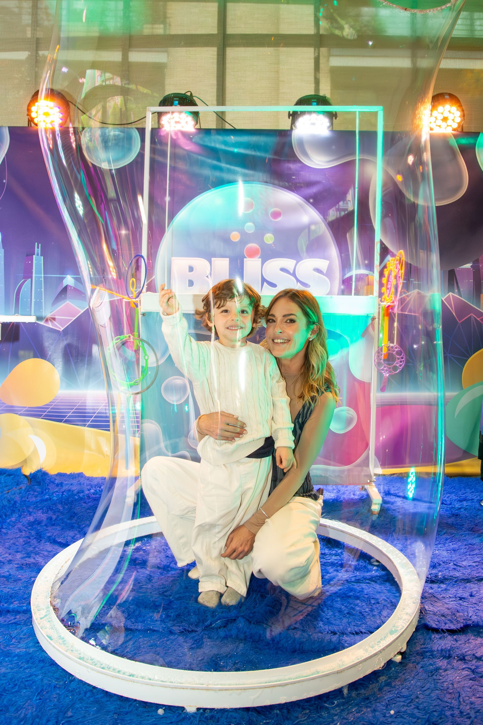 Mujer y niño dentro de una gran burbuja, frente a un fondo colorido de 