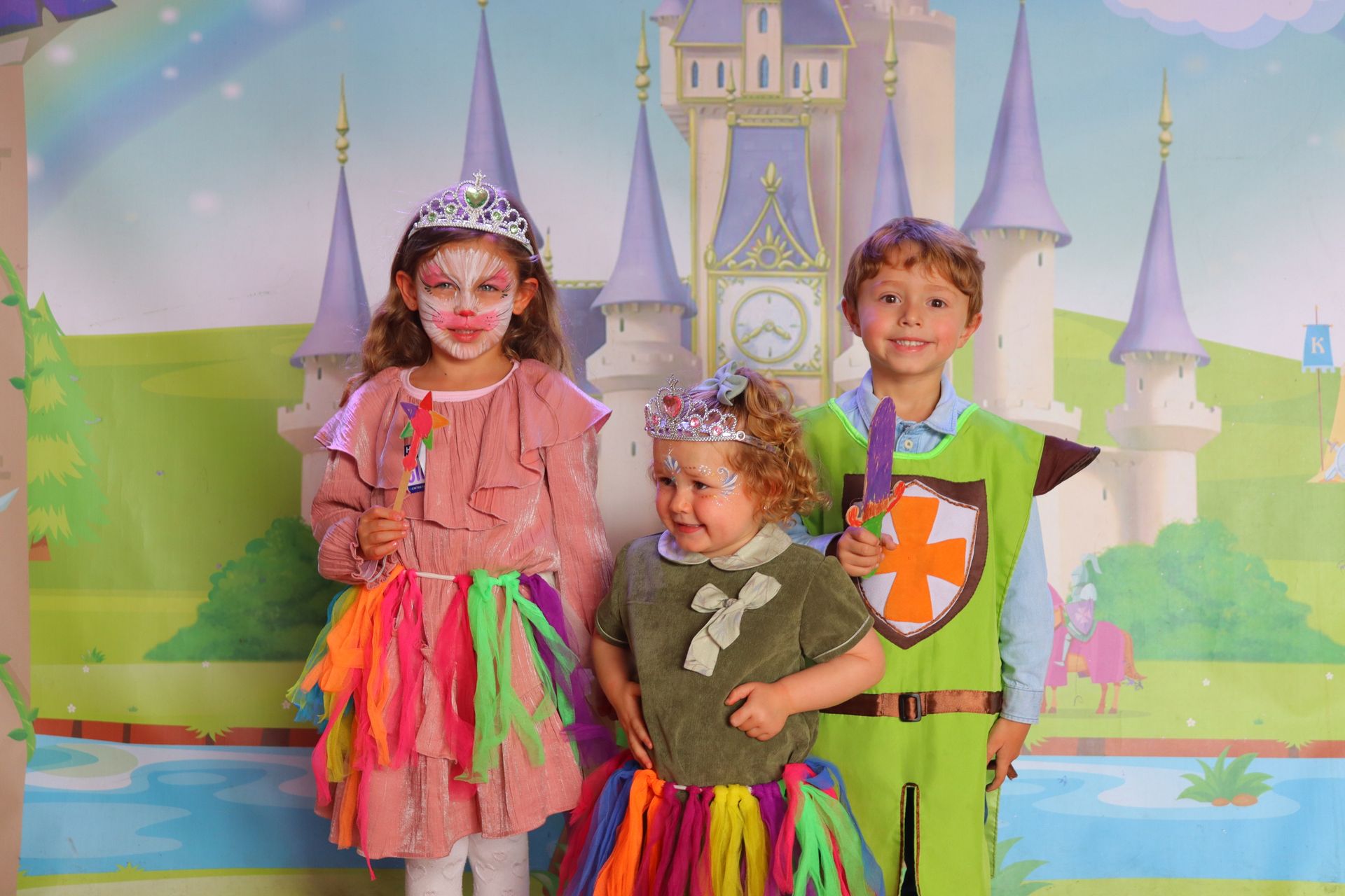 Tres niños disfrazados posan para una foto frente a un castillo.