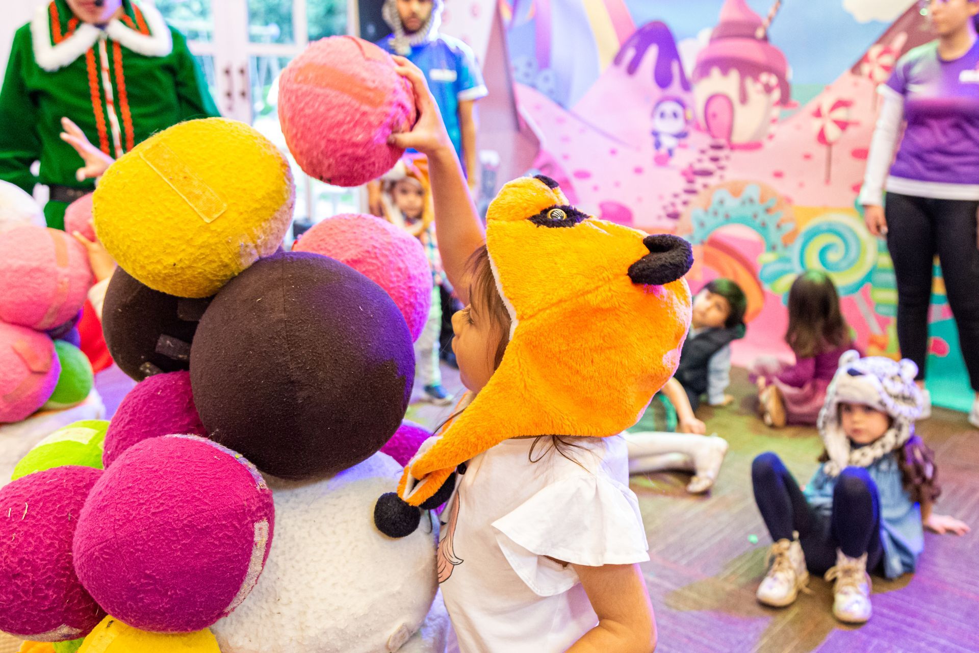 Una niña que lleva un sombrero de zorro está jugando con bolas de caramelo.
