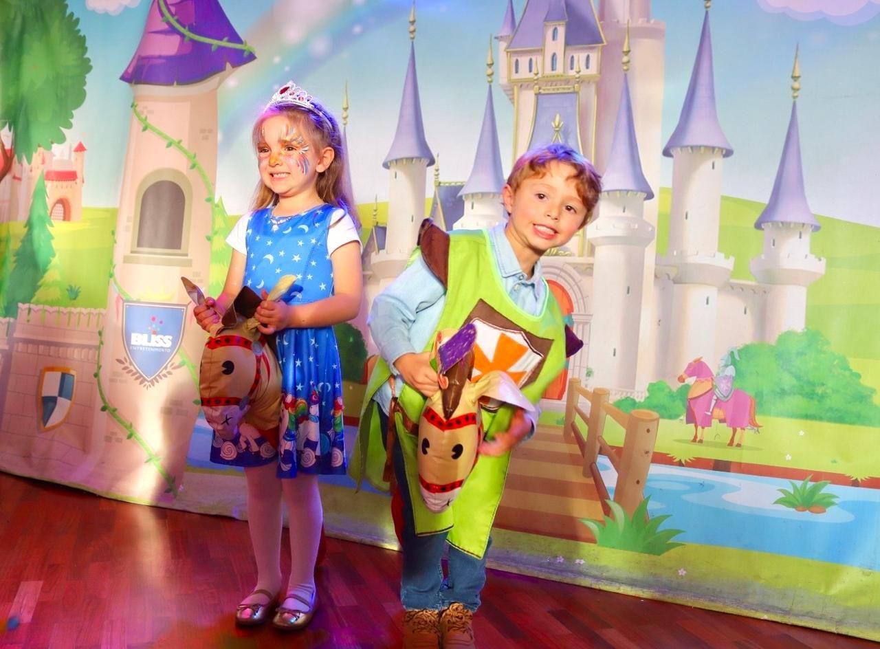 Un niño y una niña están parados uno al lado del otro frente a un castillo.