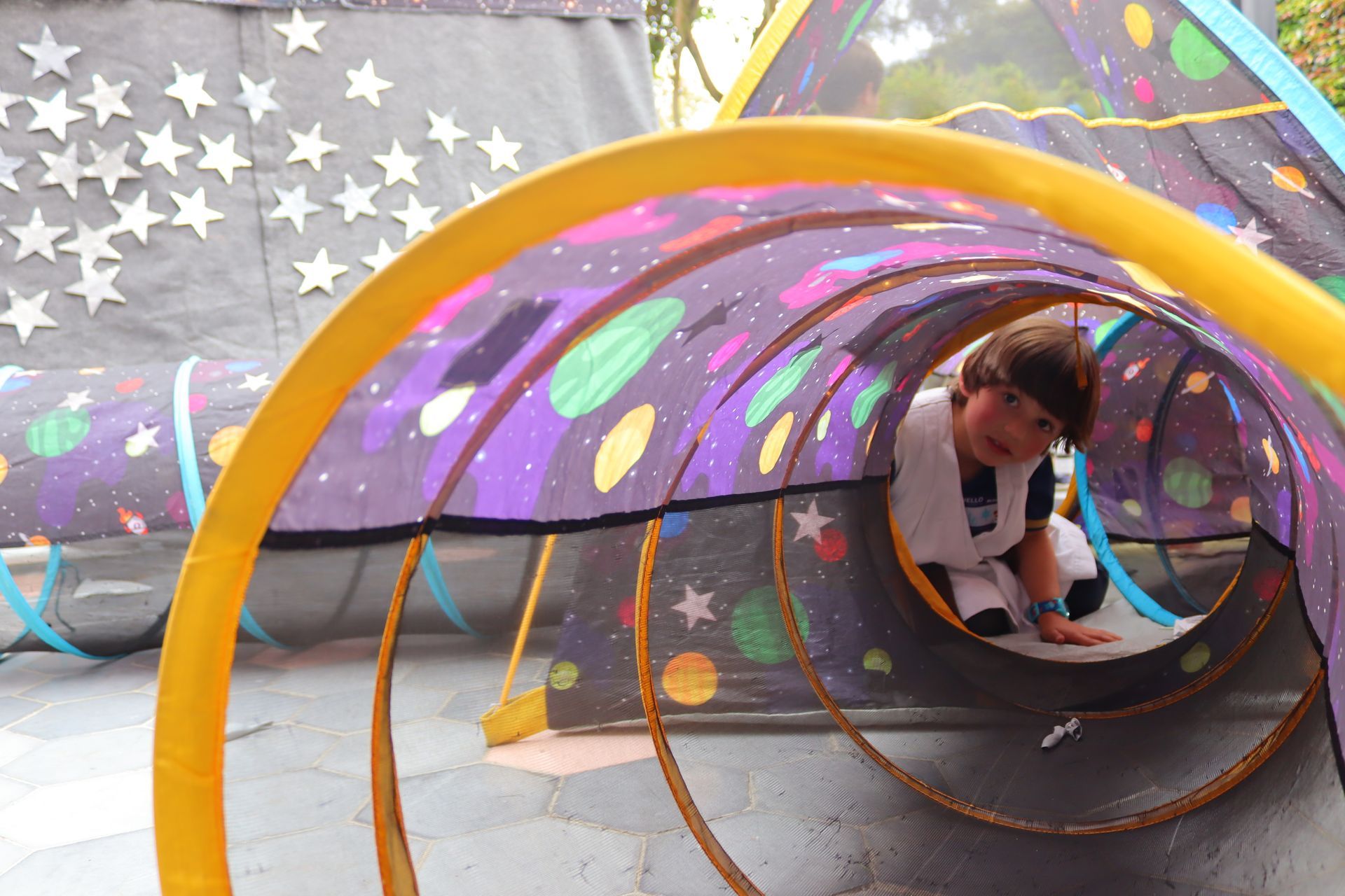 Un niño se arrastra por un túnel con una bandera estadounidense en el fondo.