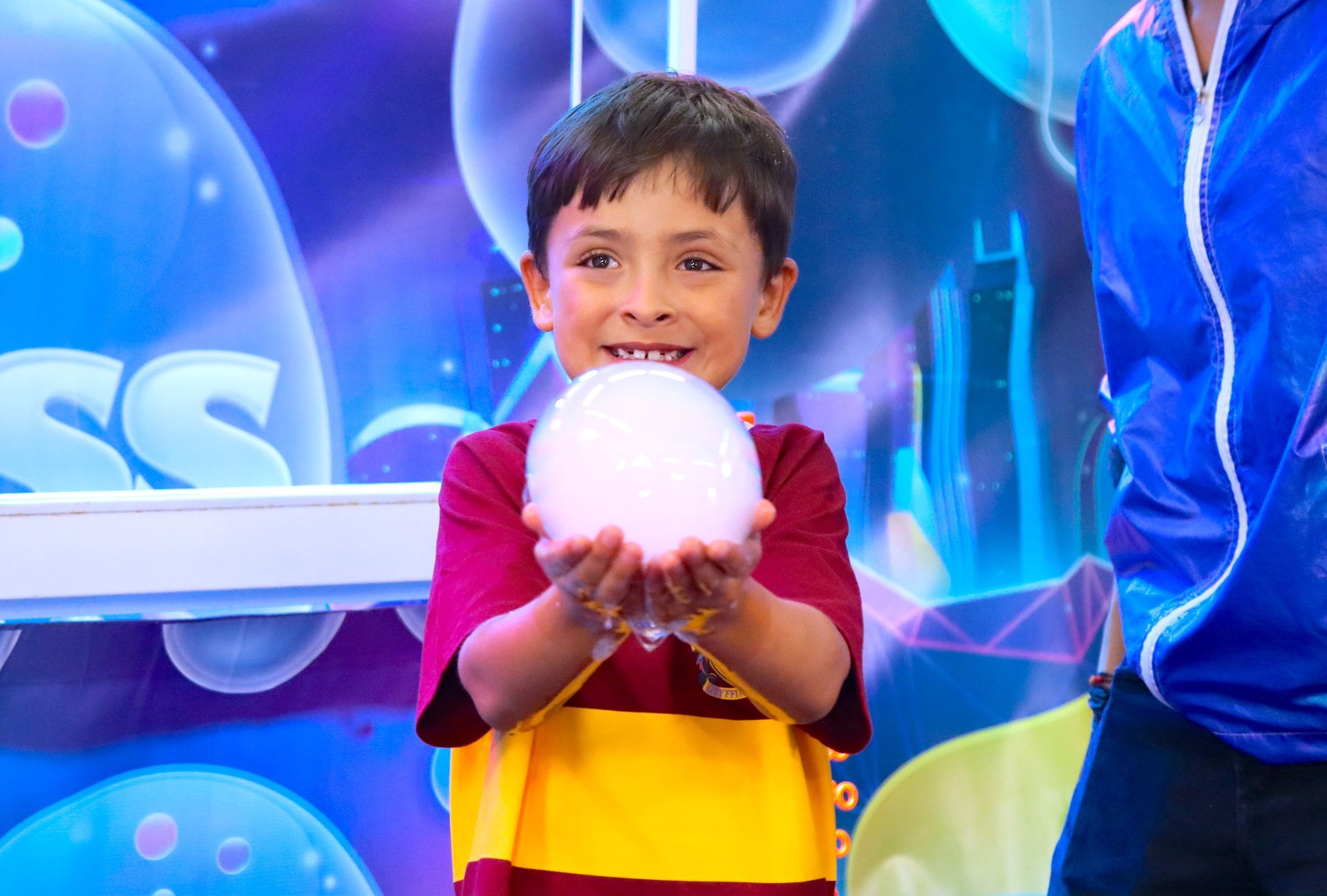 Un niño pequeño sostiene una bola de burbujas de jabón en sus manos.