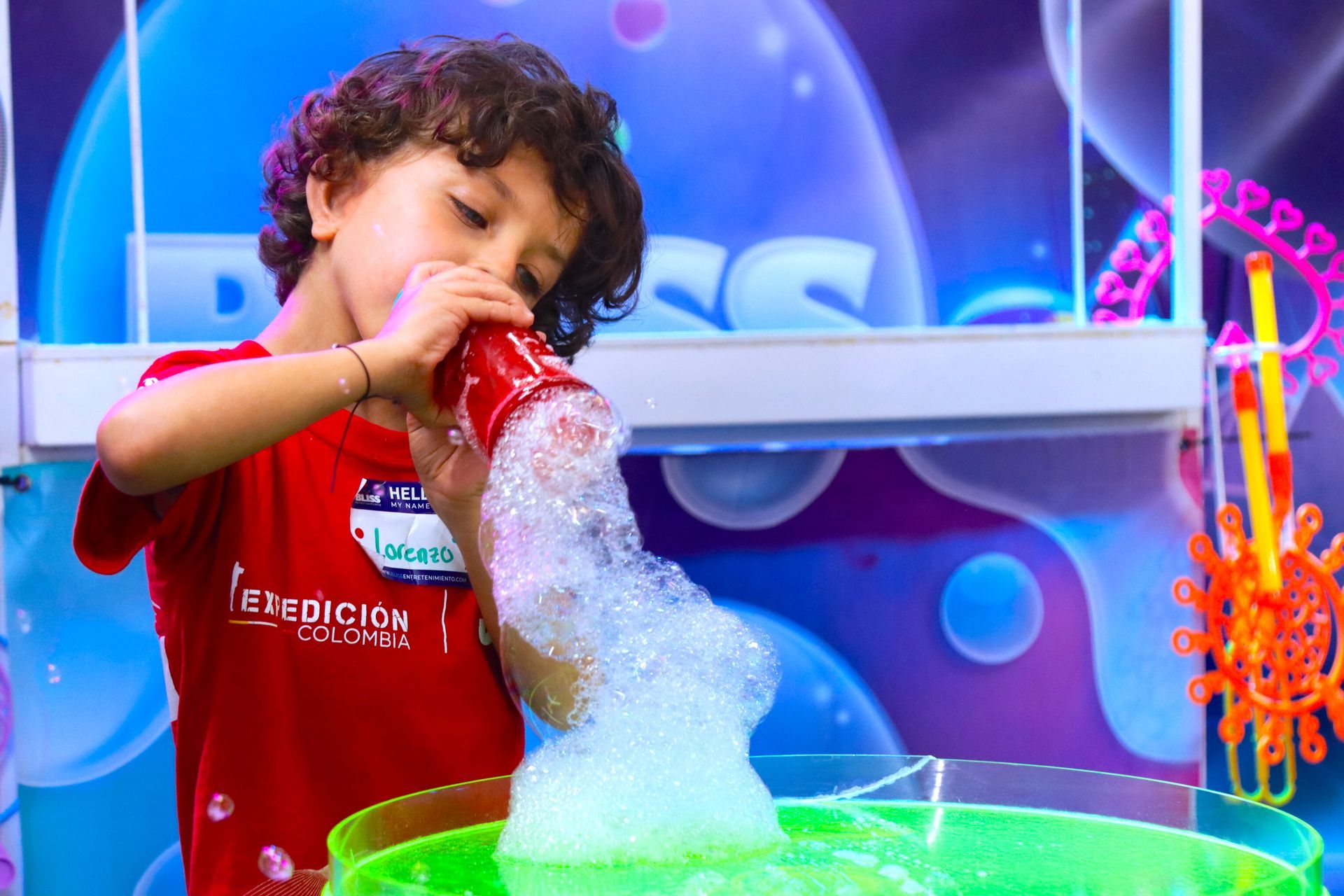 Un niño pequeño está vertiendo burbujas de jabón en un recipiente.