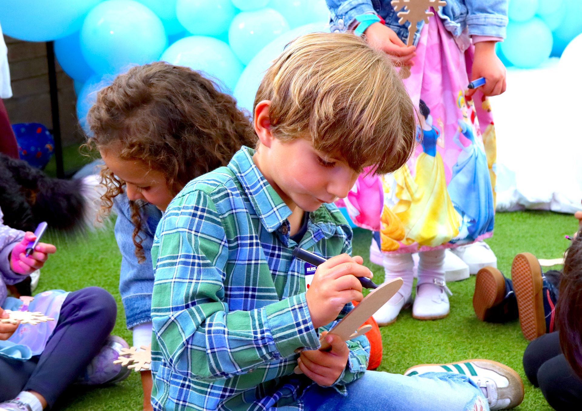 Un grupo de niños está sentado en el césped jugando con juguetes.