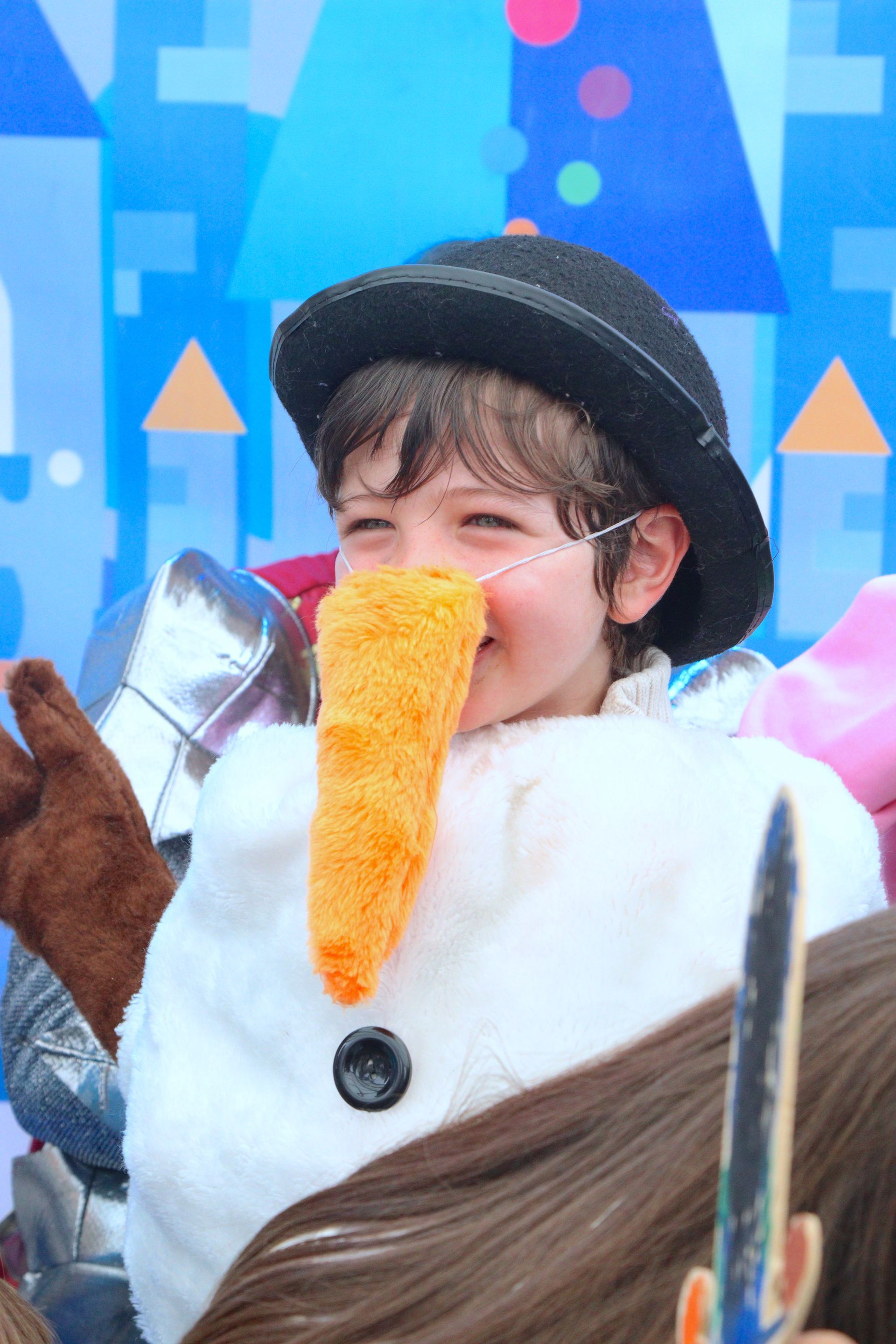 Un niño vestido de muñeco de nieve con una nariz naranja.