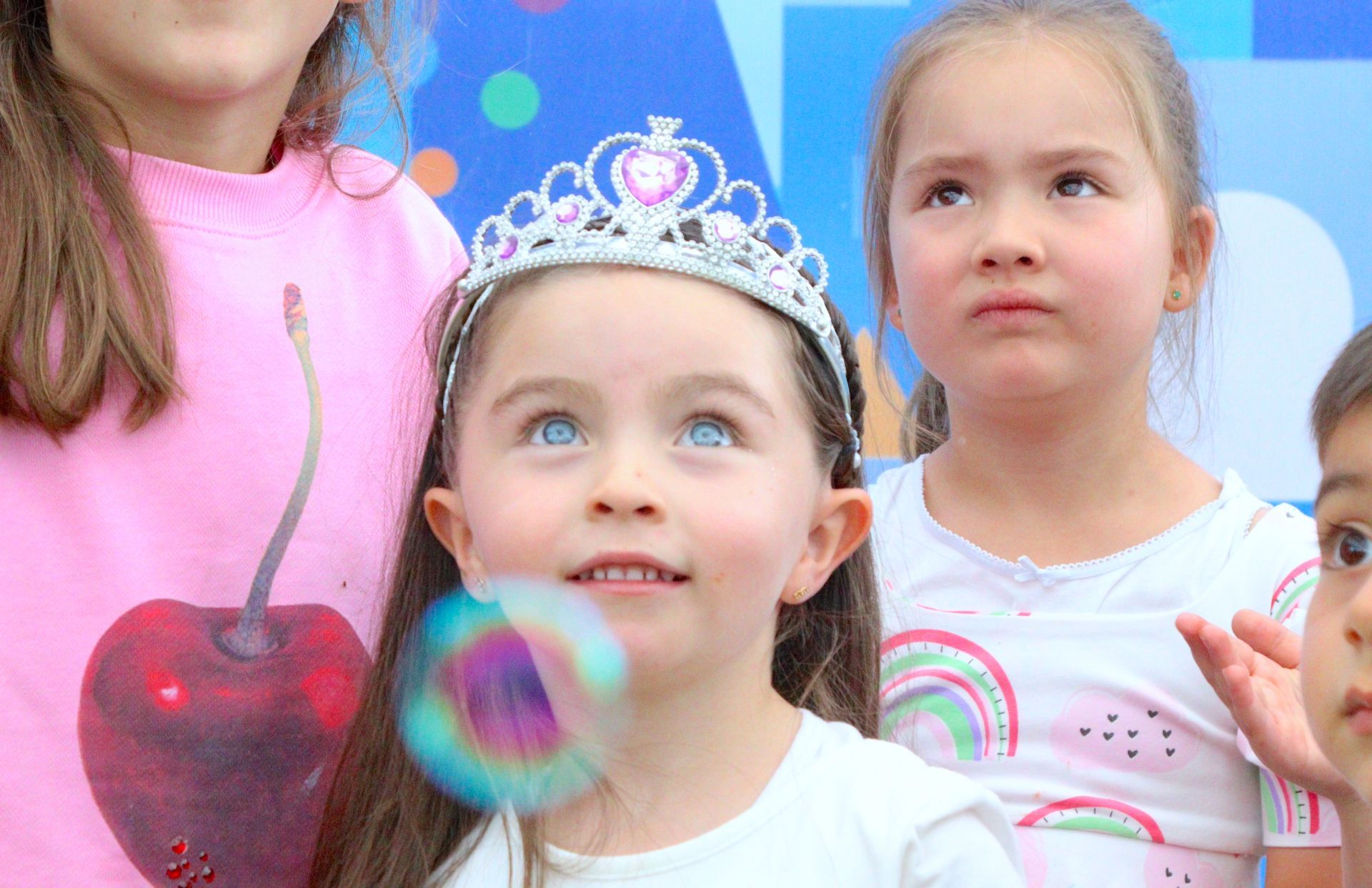 Una niña que lleva una tiara está soplando burbujas de jabón.