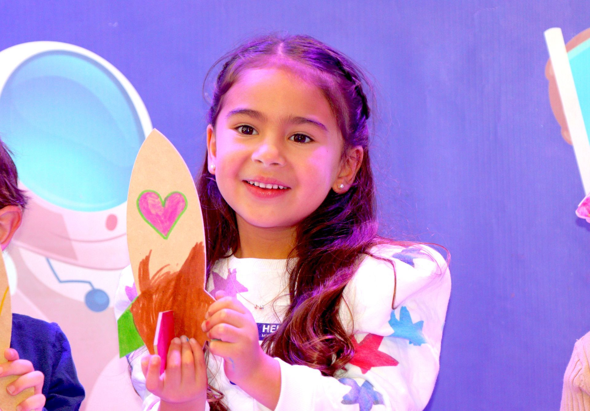 Una niña sostiene un trozo de papel con un corazón.