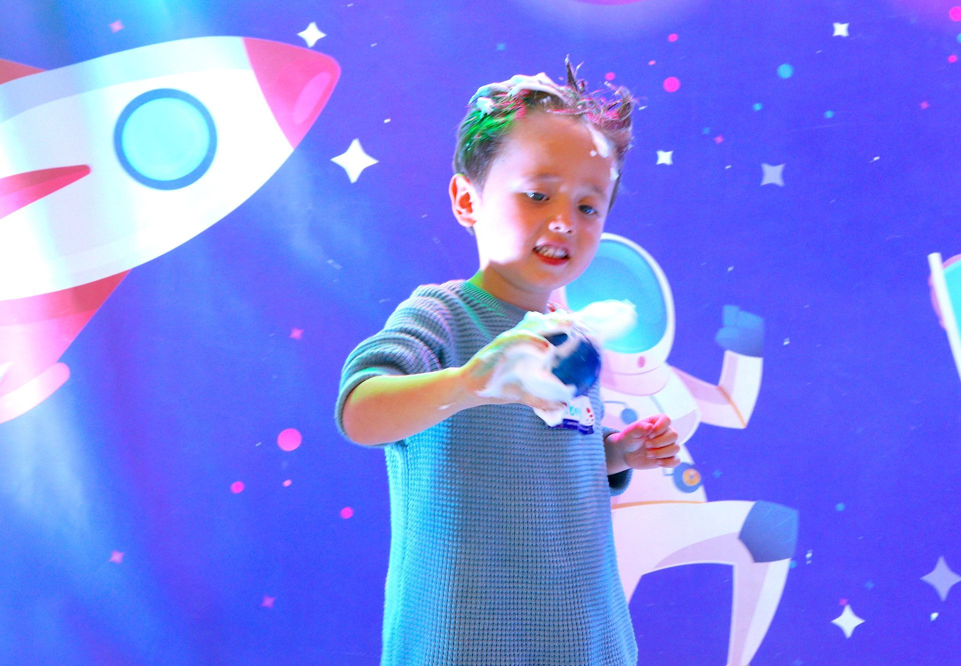 Una niña está parada frente a un fondo azul con un cohete en el fondo.